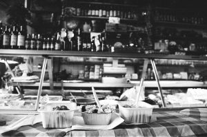 Black and white photo of food in containers at a deli counter