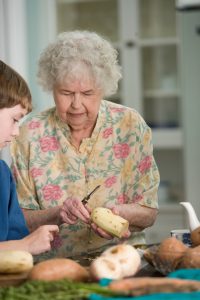 An older woman showing a young child how to peel a potato