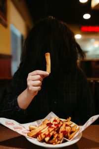 Silhouette of a woman holding a french fry